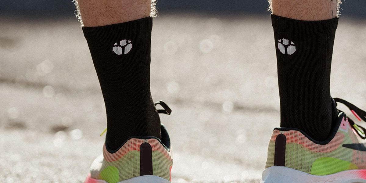 Black Fractel crew socks with the logo worn with bright running shoes, part of our running accessories range