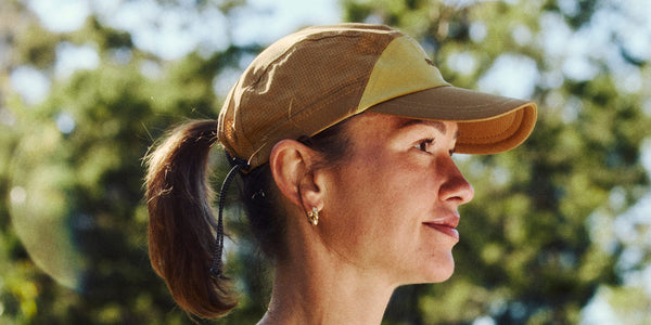Woman in profile wearing a tan Fractel E-Series running cap for smaller heads with her ponytail through the back
