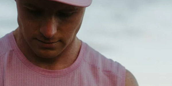 Runner in a pink Fractel singlet and cap looking down, featured in our gifts for runners collection