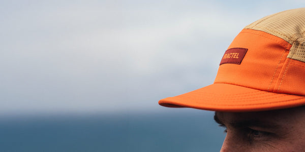Close-up of an orange and tan Fractel M-Series running cap with a red Fractel patch above the sea